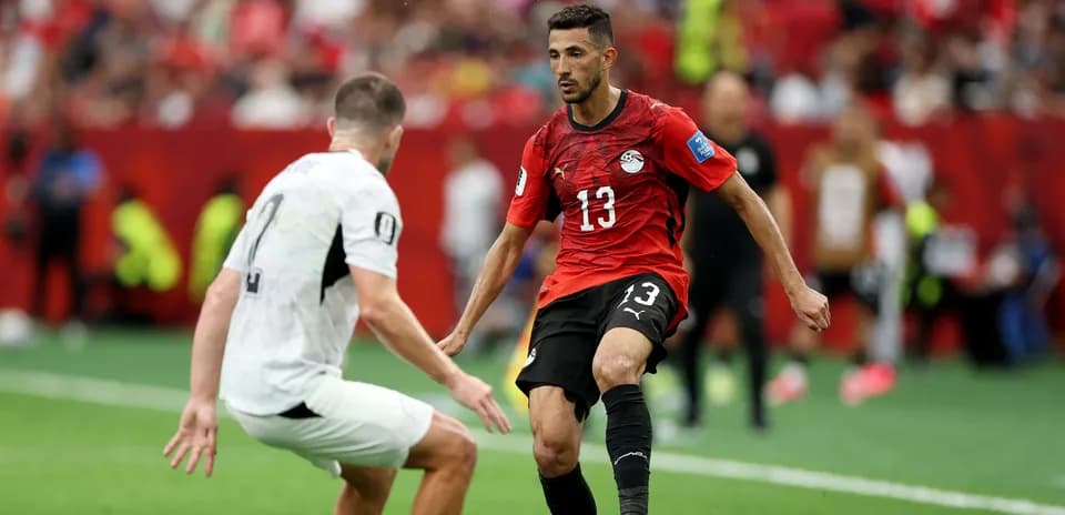 Player in red jersey dribbling past opponent in white