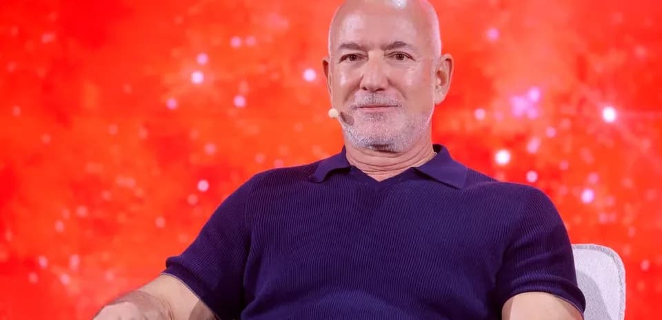 Man seated on stage with red background