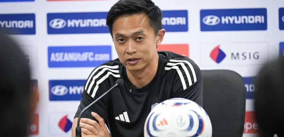 Coach speaking at press conference with soccer ball