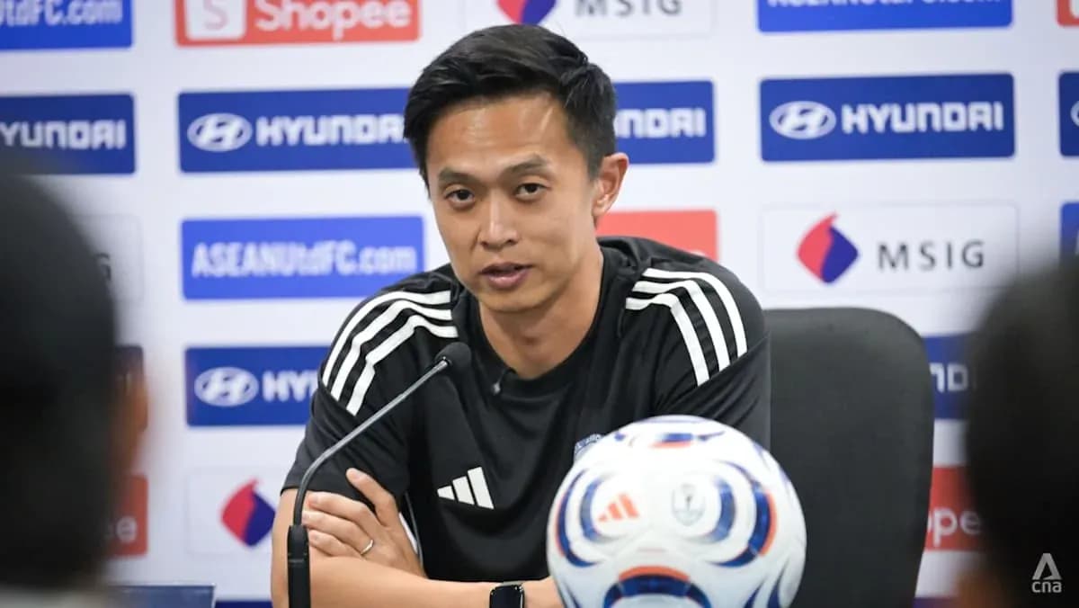 Coach speaking at press conference with soccer ball