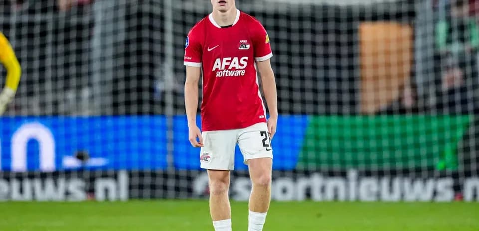 Player in red jersey standing on football pitch