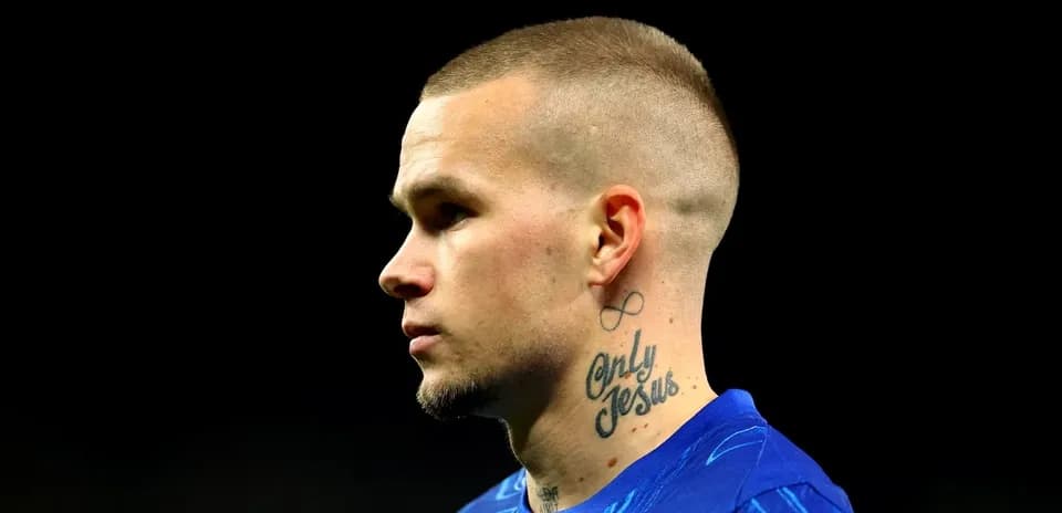 Player with tattoos wearing blue jersey, profile view