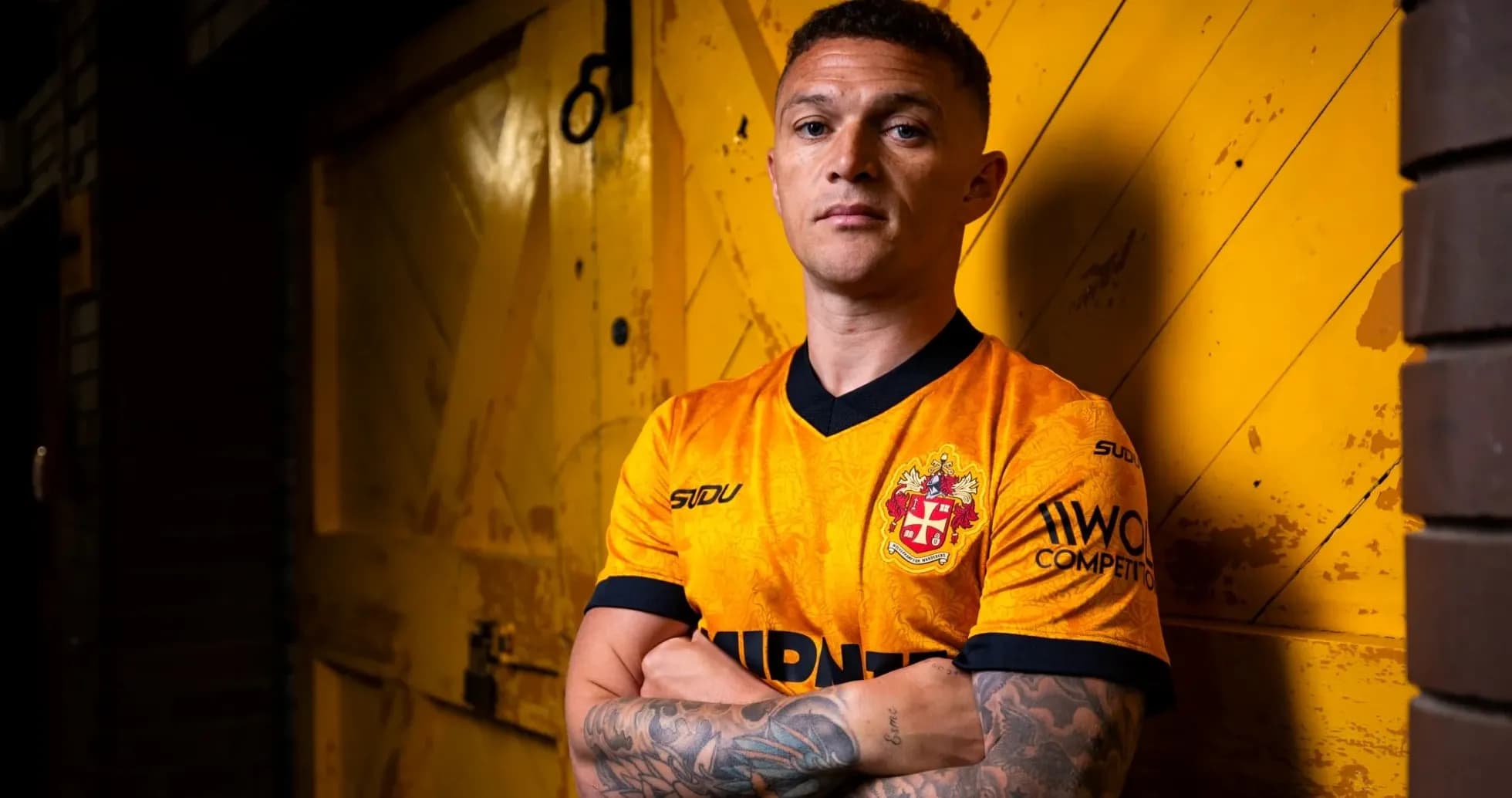 Player posing in orange football jersey against yellow background