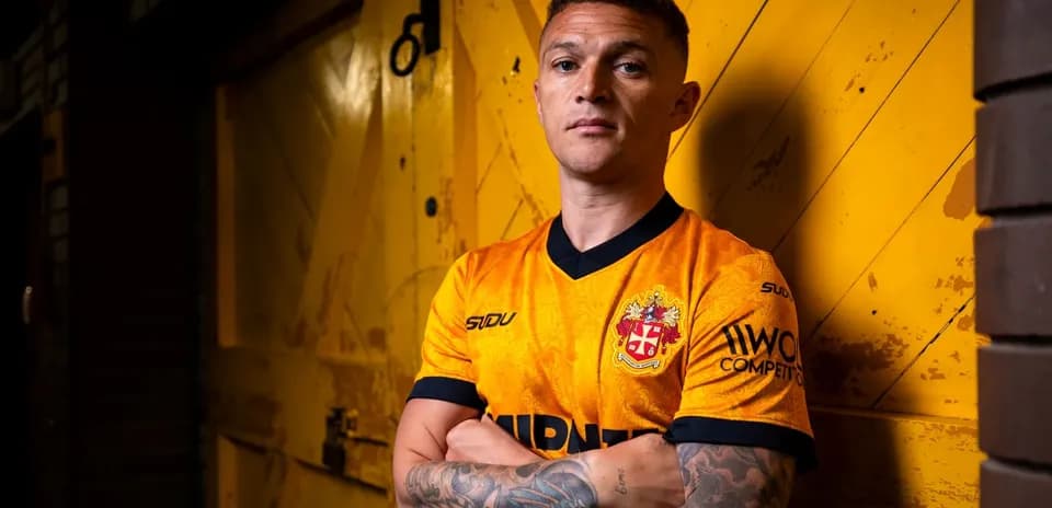 Player posing in orange football jersey against yellow background