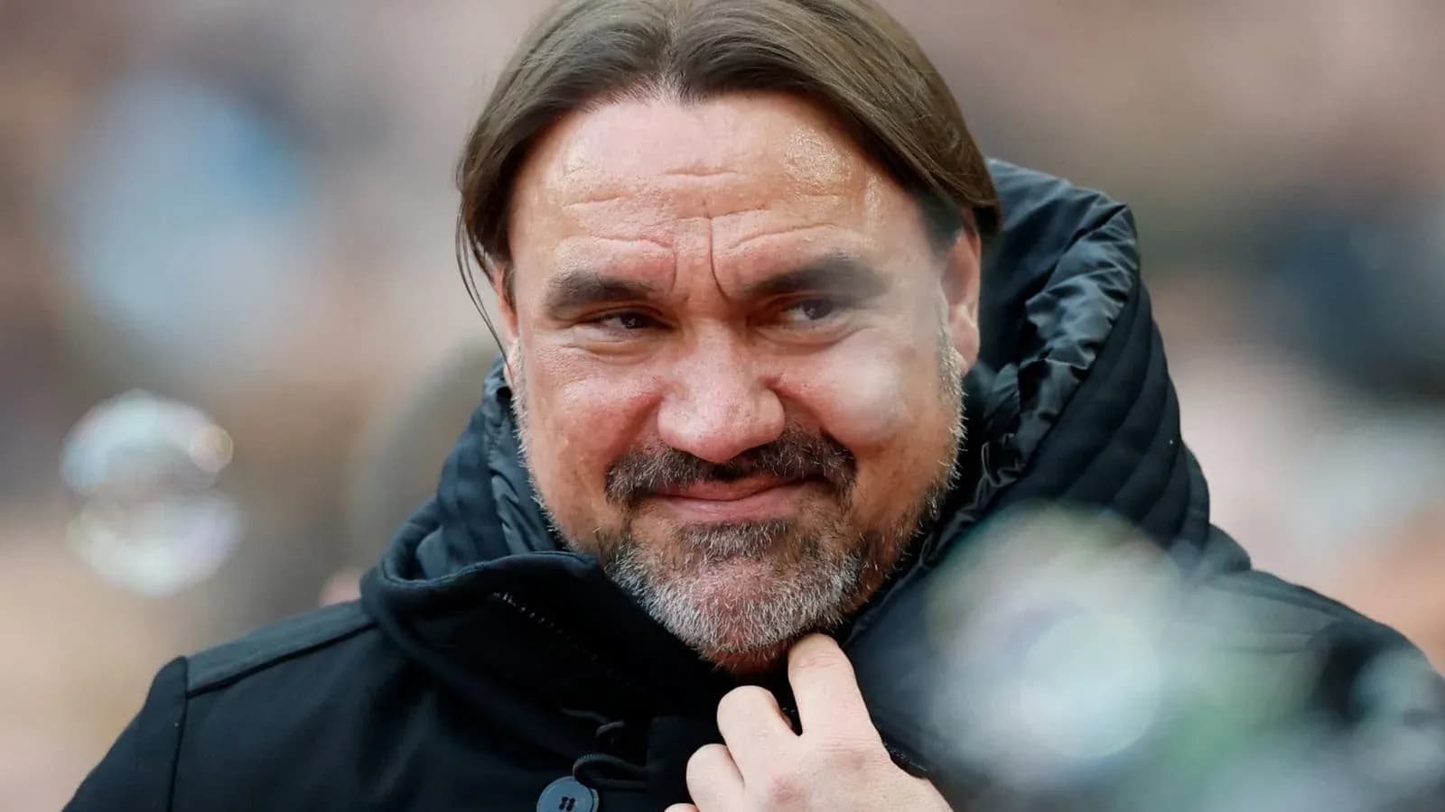 Coach wearing a black jacket, smiling slightly