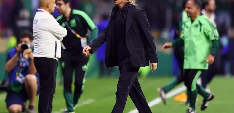 Coach walking past staff on the pitch