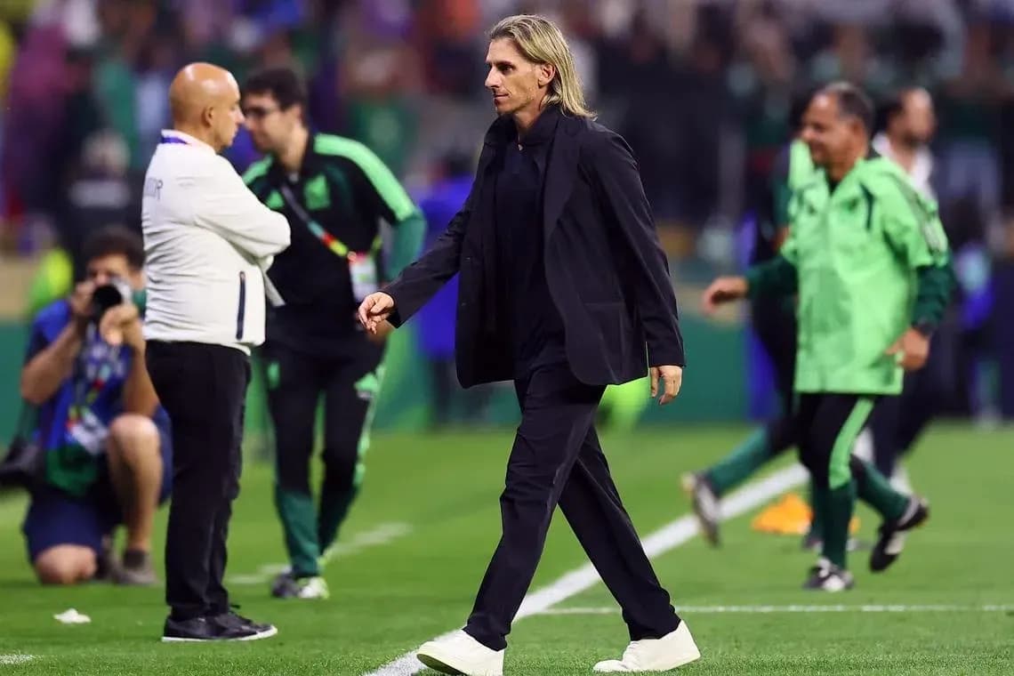 Coach walking past staff on the pitch
