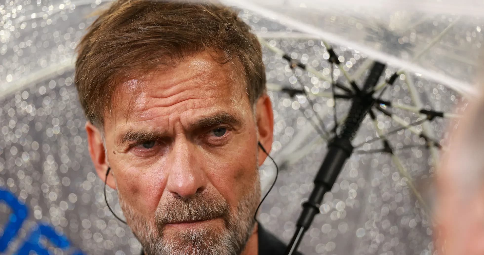 Coach speaking under umbrella during rainy event