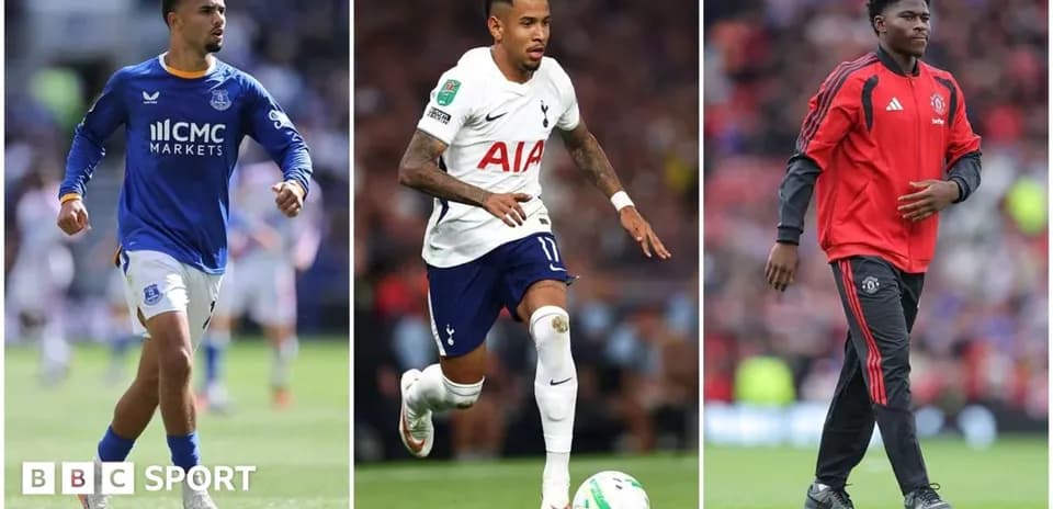 Three football players in club kits on pitch