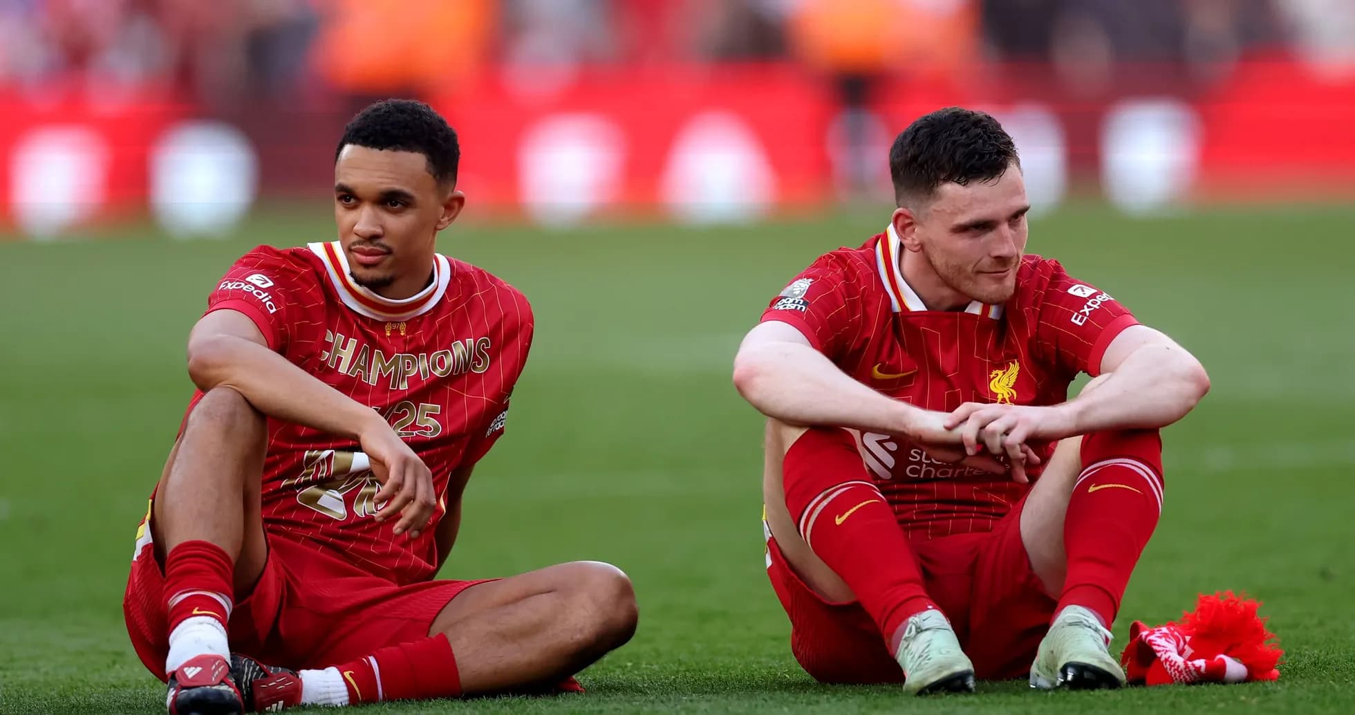 Two Liverpool players sitting on pitch after match