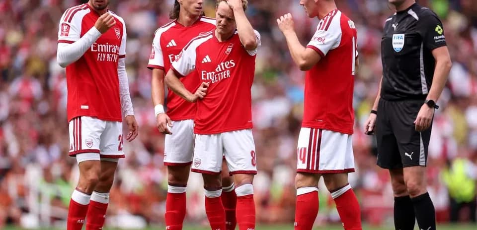 Arsenal players discussing a set piece with referee