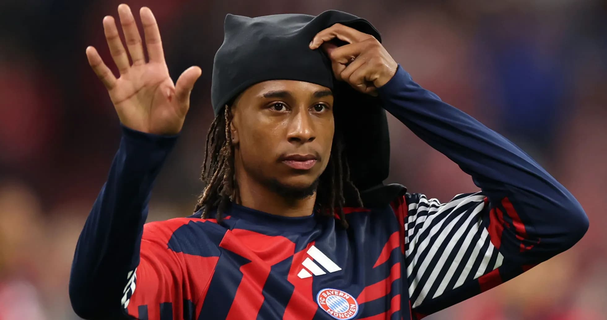 Player waving while adjusting headwear on field