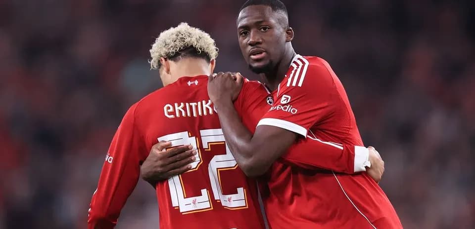 Two players embracing on the field in red jerseys