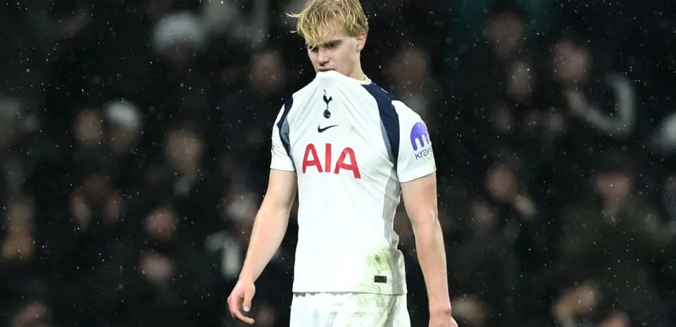 Player looking down, wearing Tottenham kit in rain