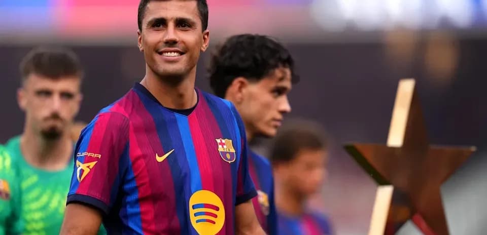 Barcelona player smiling with teammates and trophy