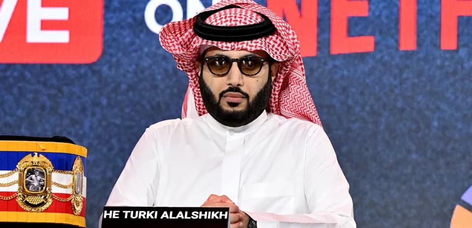 Man in traditional dress at press conference table