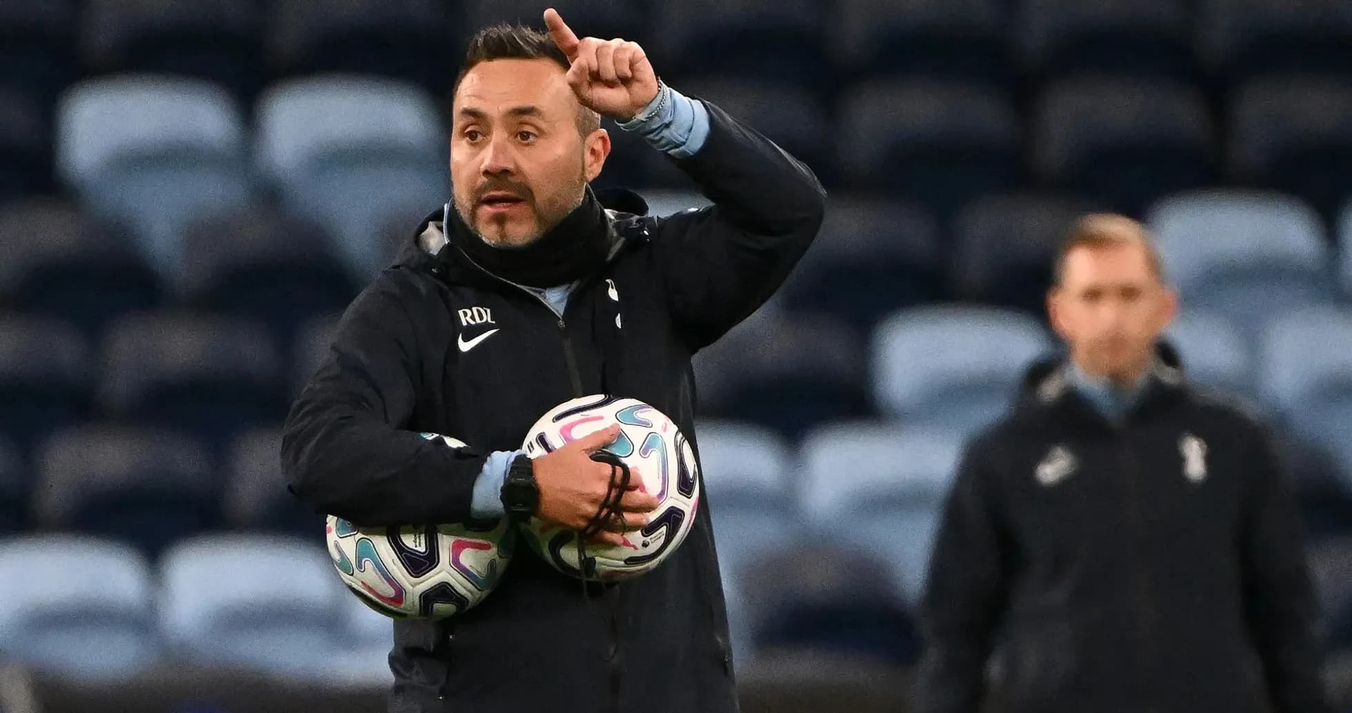 Coach instructing players while holding soccer balls