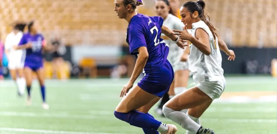 Player in purple dribbling past opponent in white