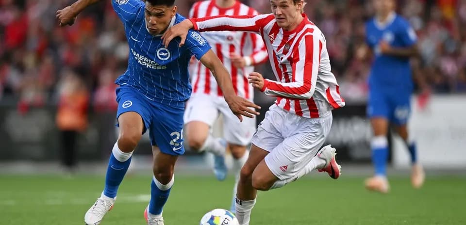 Player in blue jersey evading opponent in red stripes