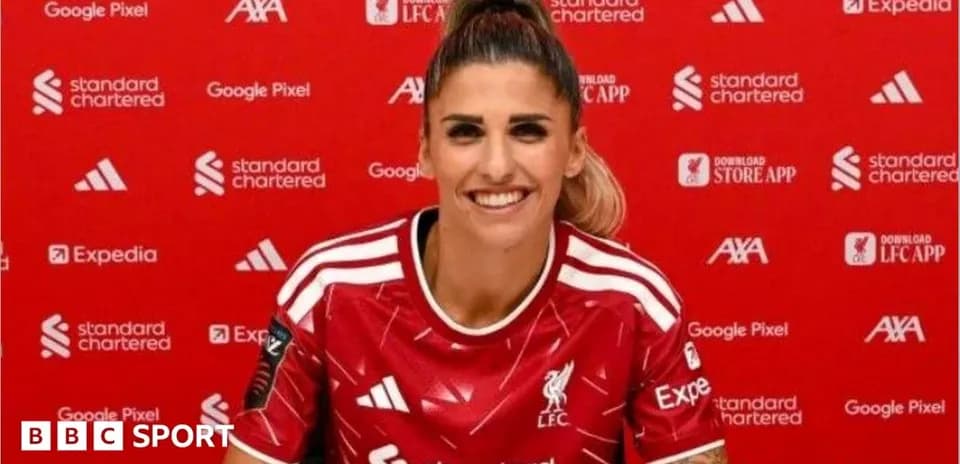 Player smiling in Liverpool FC jersey at press event
