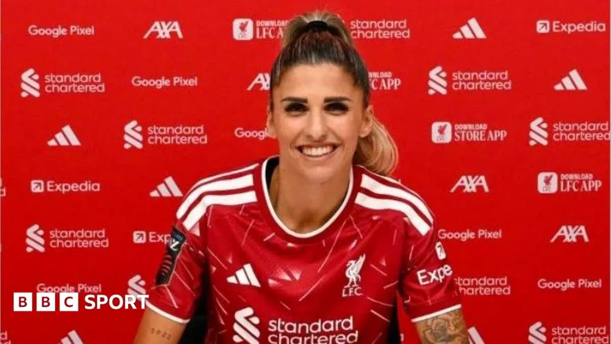 Player smiling in Liverpool FC jersey at press event