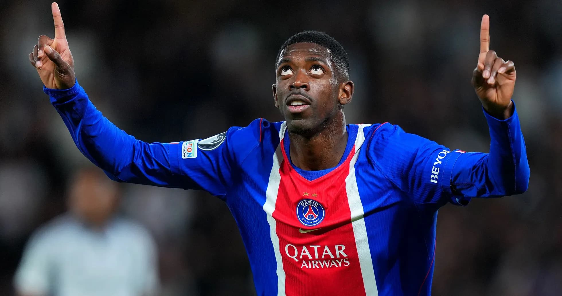 Player celebrating goal with arms raised in PSG jersey