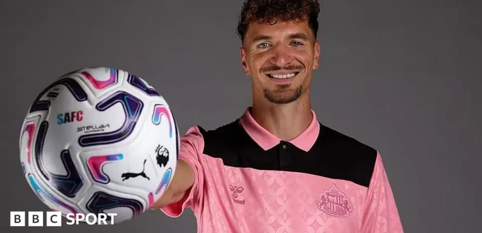 Player holding a football and smiling at camera