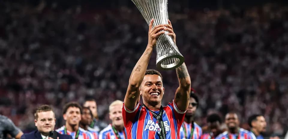 Player holding trophy with team celebrating in background