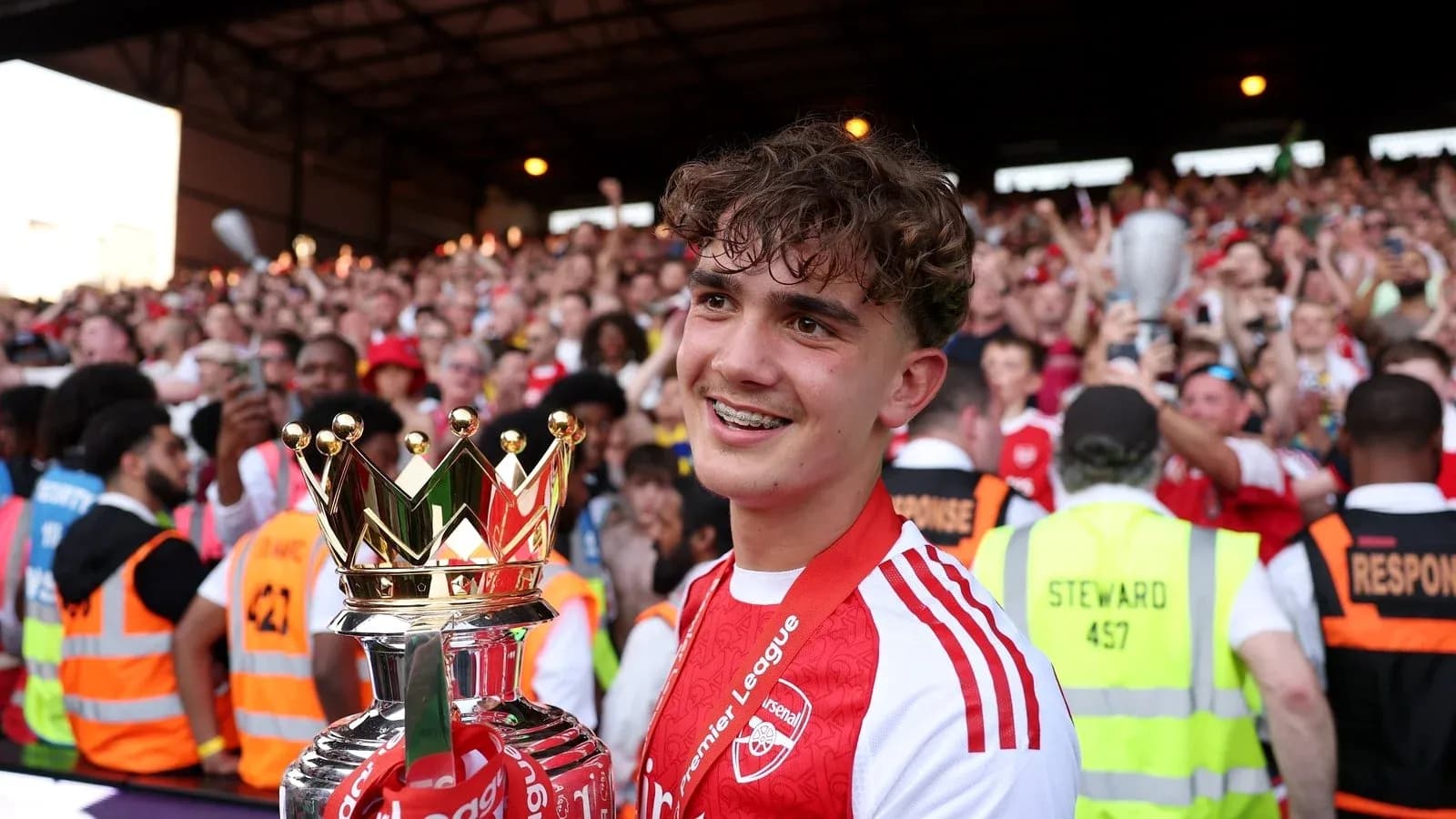 Player celebrating with Premier League trophy and fans