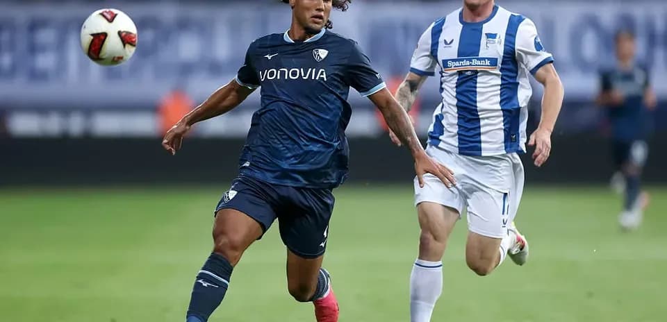 Player in blue jersey dribbling past opponent in white