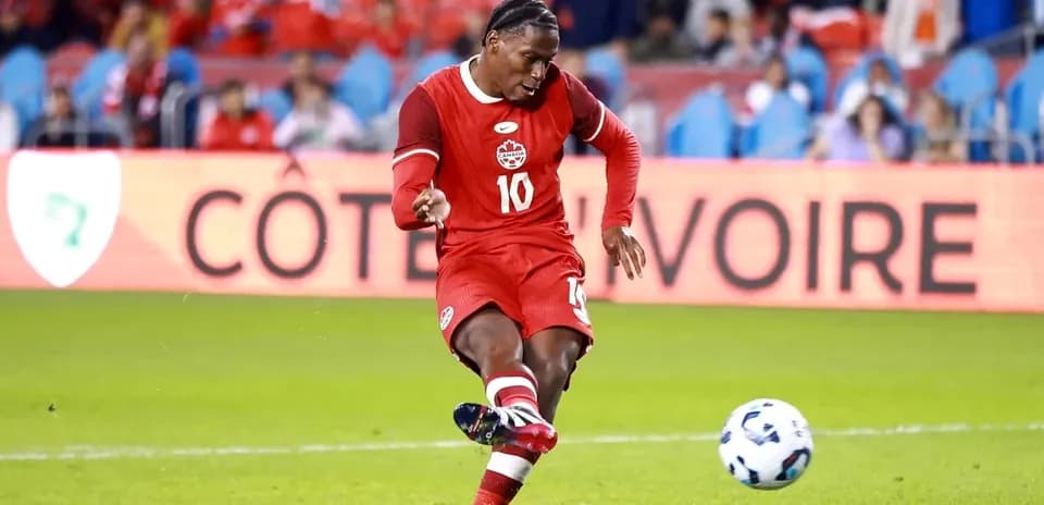 Player kicking ball during soccer match in red uniform