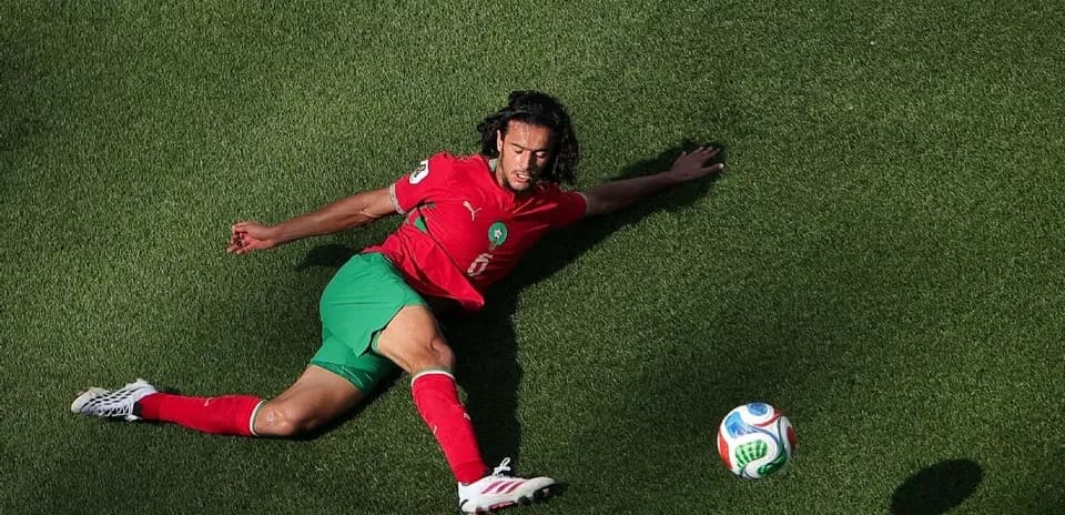Player in red and green uniform on grass field
