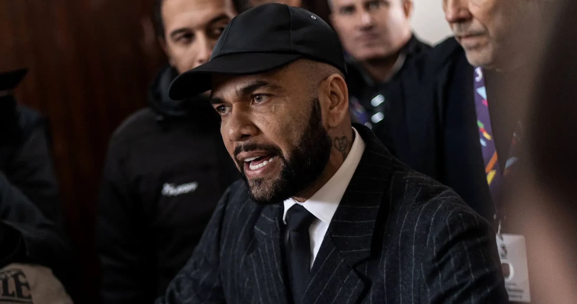Man speaking during a press conference surrounded by others