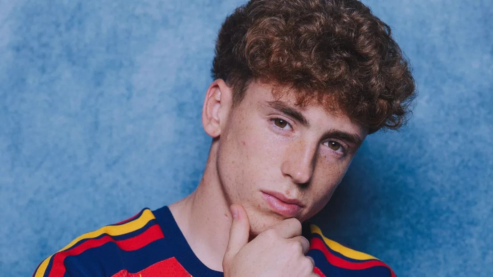 Young man with curly hair posing thoughtfully