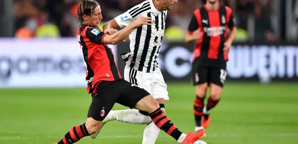 Player from AC Milan tackling Juventus player during match