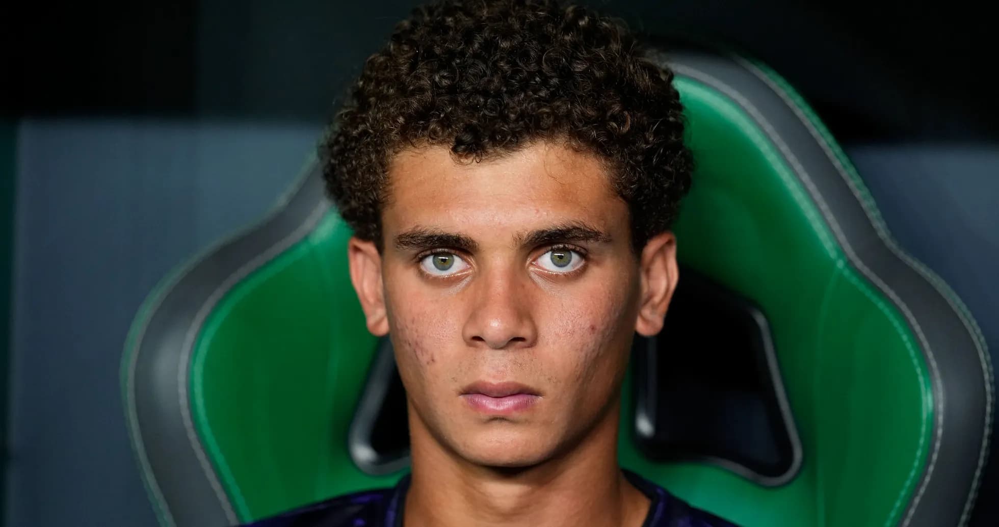Young athlete sitting on green gaming chair