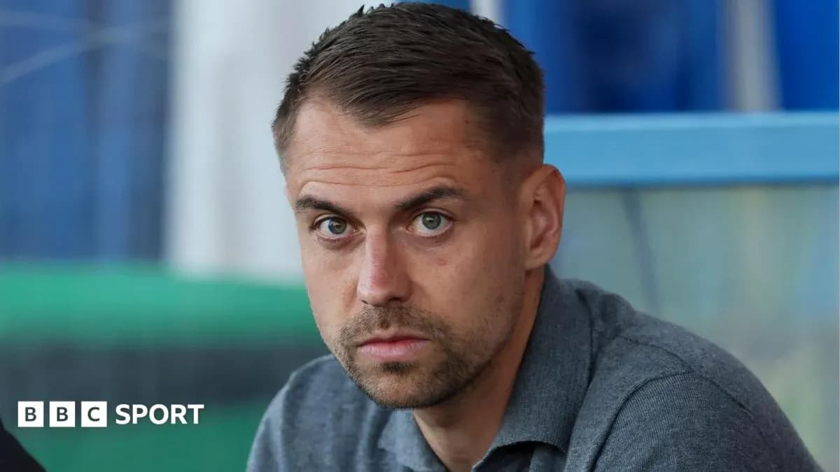 Man with short hair sitting in a stadium