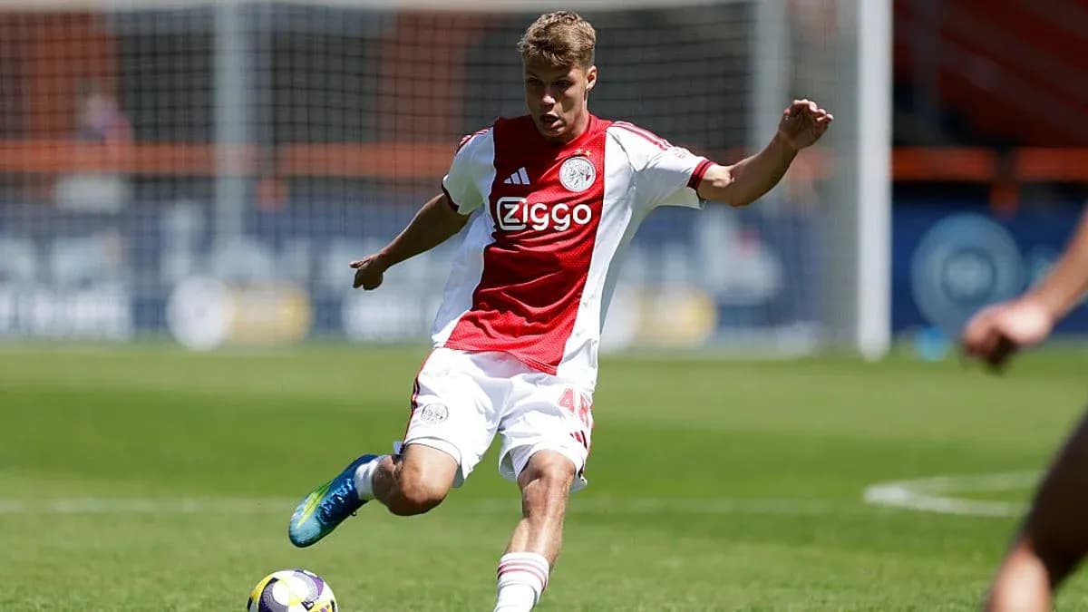 Player in Ajax kit striking the ball on field Player in Ajax kit striking the ball on field