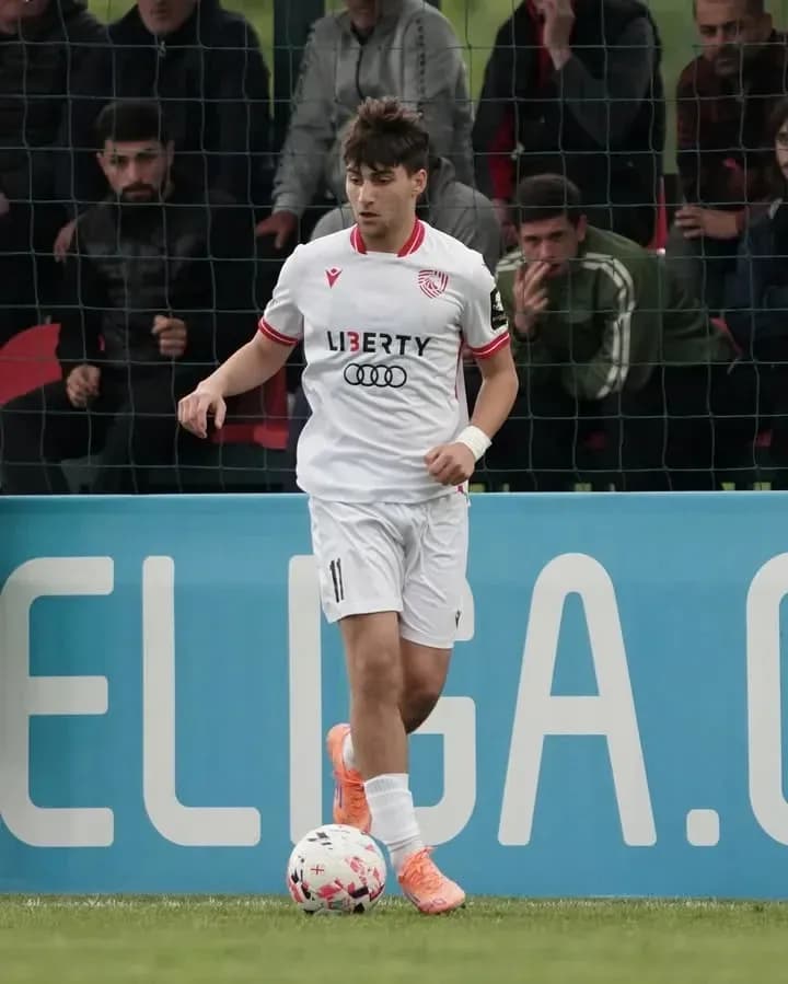 Player in white kit dribbling ball on pitch Player in white kit dribbling ball on pitch