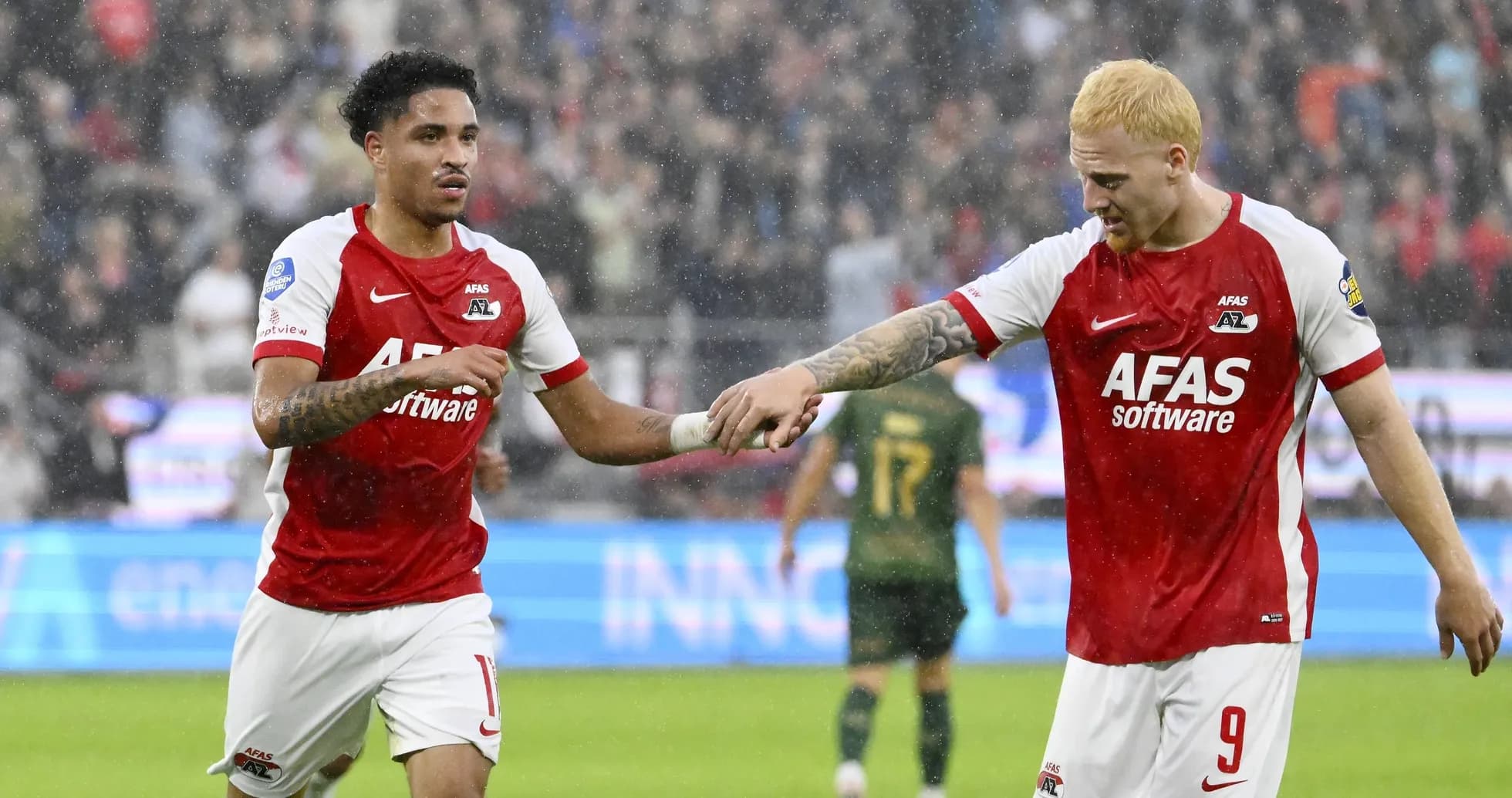 Two AZ Alkmaar players celebrating a goal in rain Two AZ Alkmaar players celebrating a goal in rain