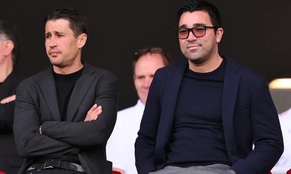 Two men seated in a sports venue box Two men seated in a sports venue box