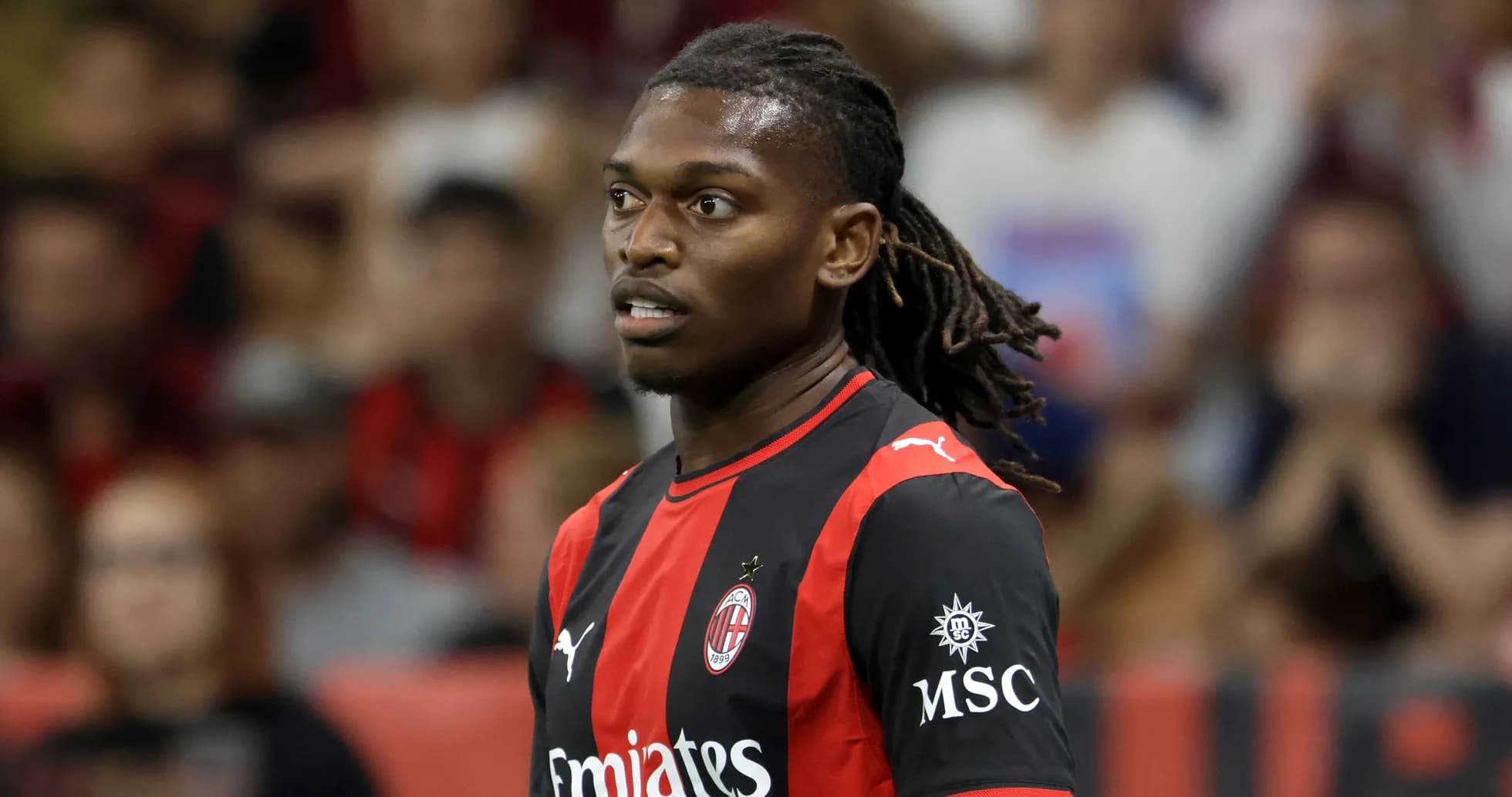 AC Milan player during match with fans in background AC Milan player during match with fans in background