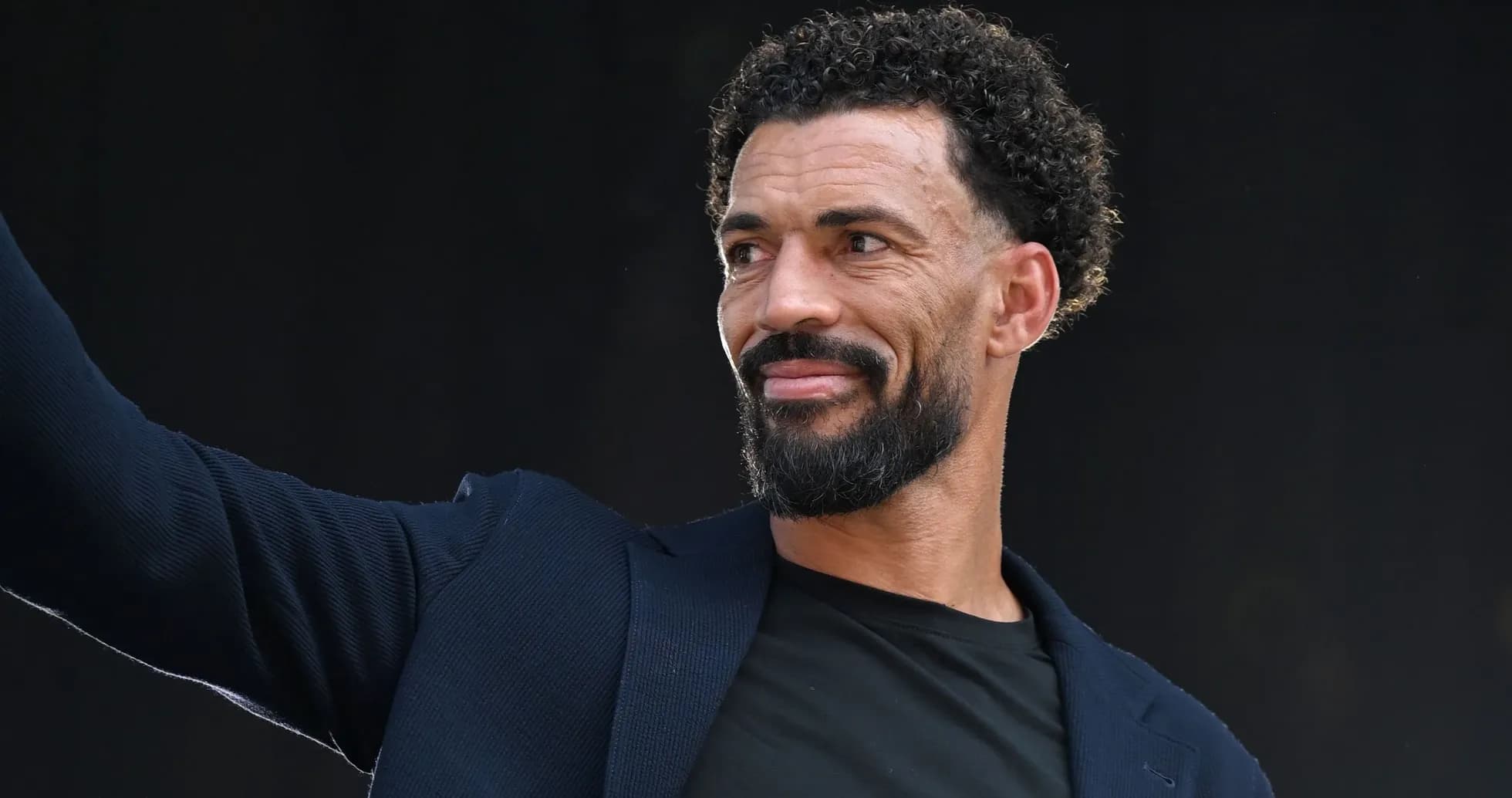 Man in a suit waving during an event Man in a suit waving during an event
