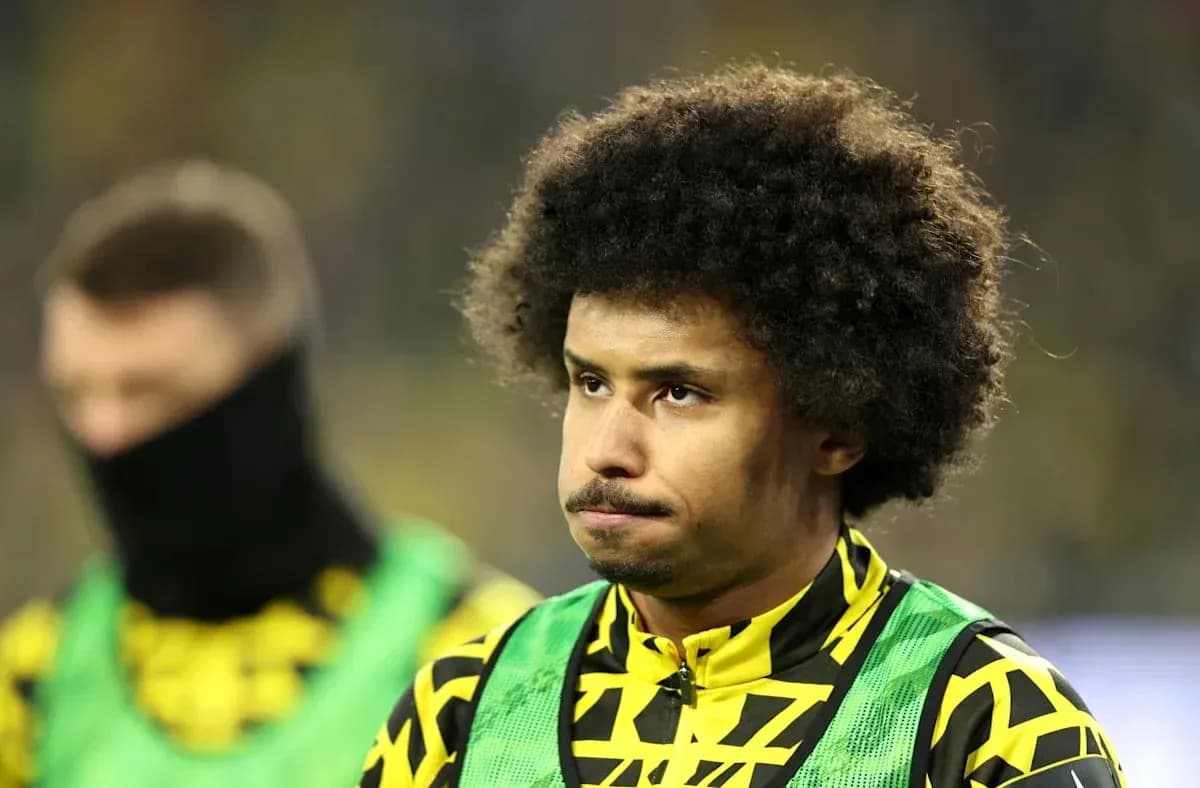 Player in yellow and black kit on the sidelines Player in yellow and black kit on the sidelines