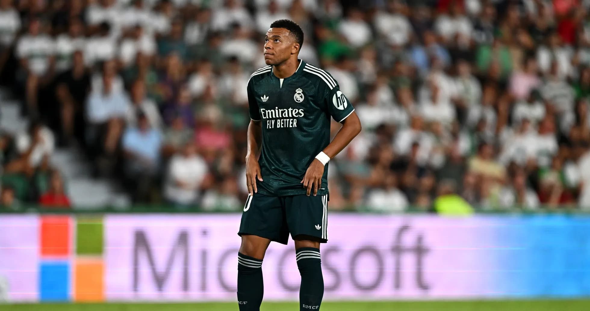 Player in green kit during match with fans in background Player in green kit during match with fans in background