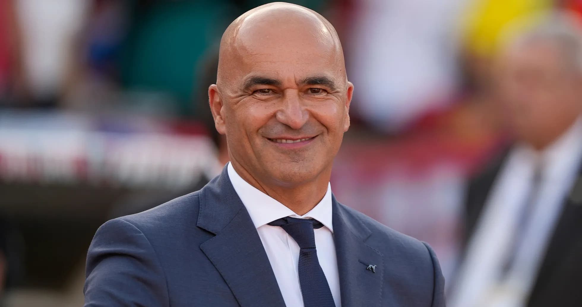 Man in suit smiling and gesturing at event Man in suit smiling and gesturing at event