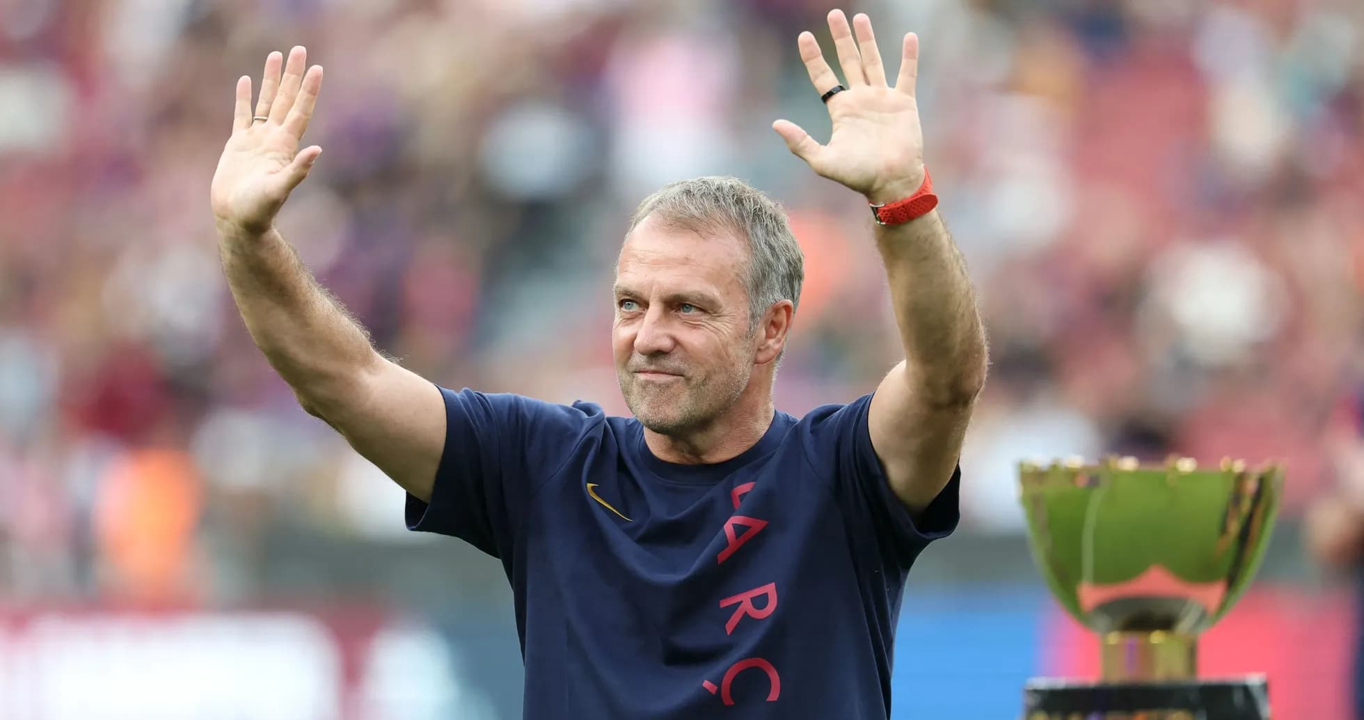 Coach waving to fans beside trophy at stadium Coach waving to fans beside trophy at stadium