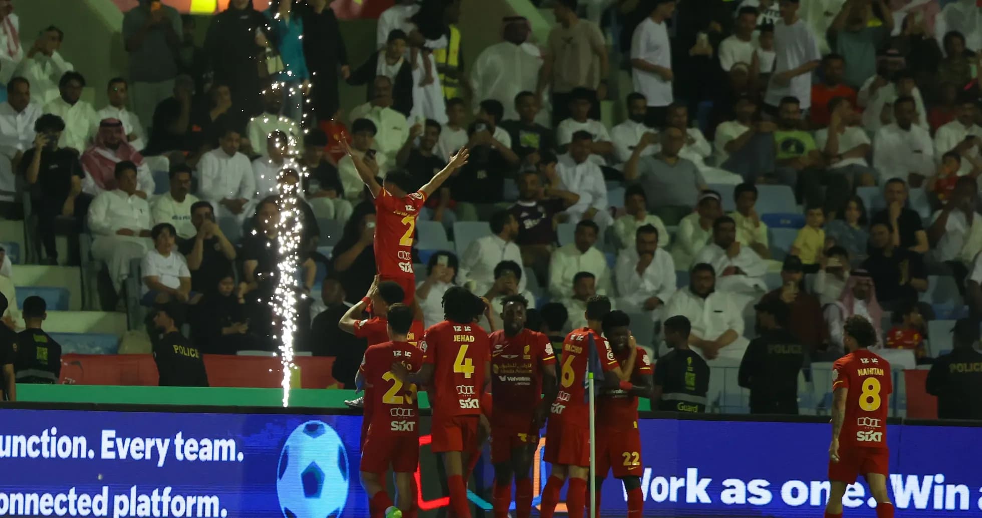 Players celebrating a goal with fireworks in stadium Players celebrating a goal with fireworks in stadium