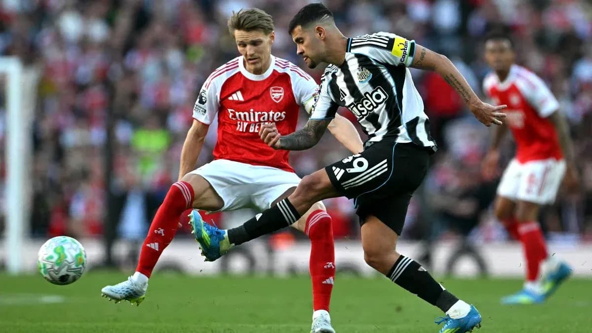Newcastle player kicking ball past Arsenal defender Newcastle player kicking ball past Arsenal defender