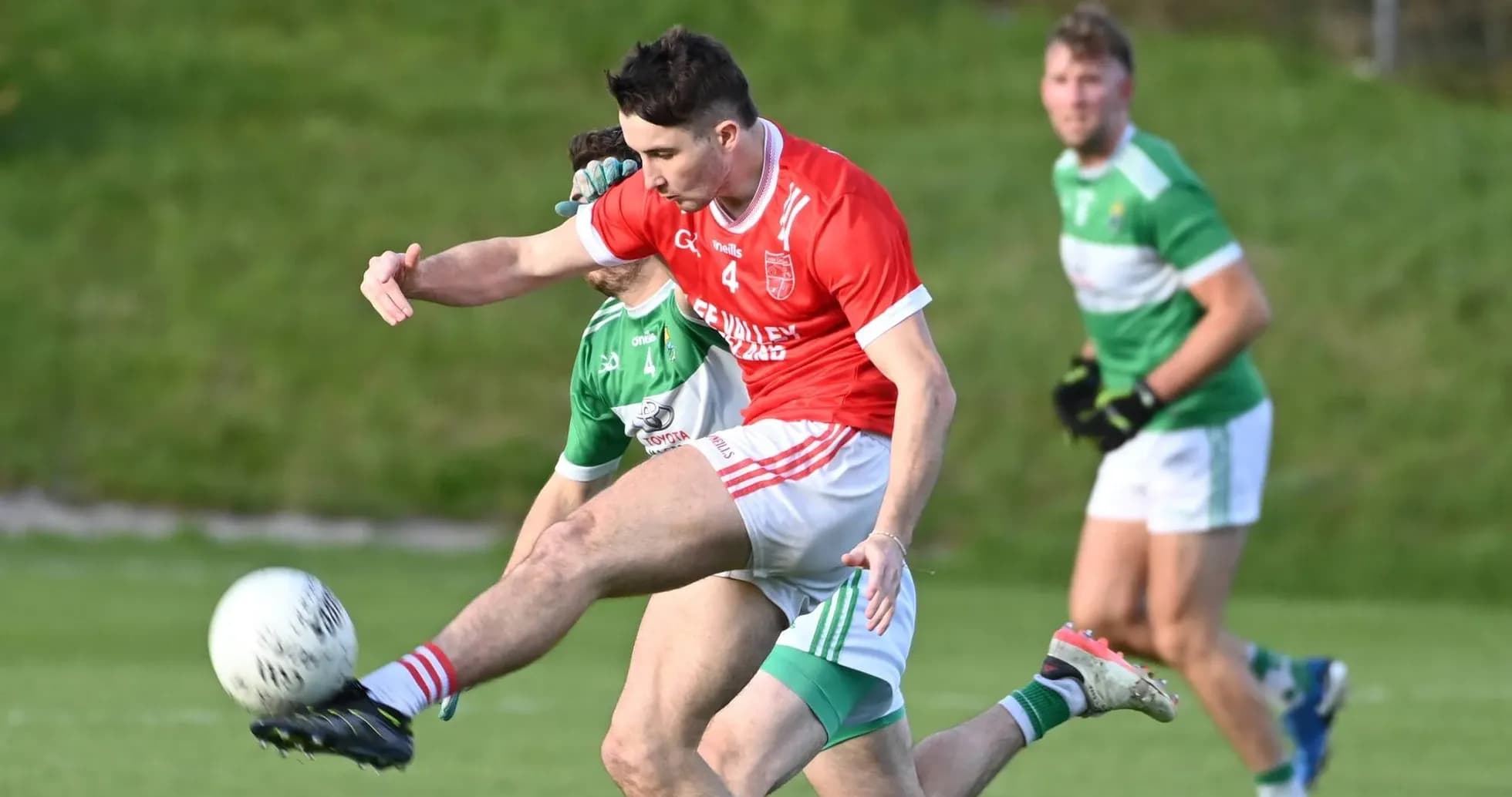 Player in red kicking ball during Gaelic football match Player in red kicking ball during Gaelic football match